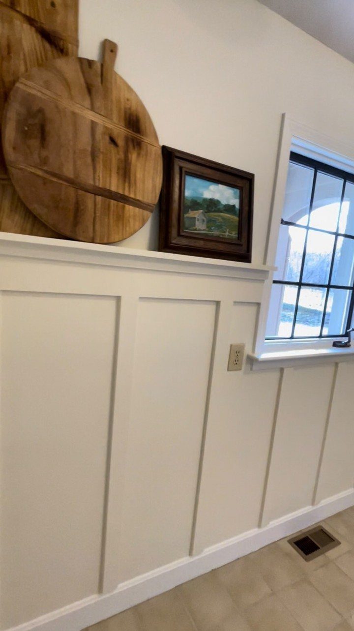 White board and batten molding installed on a cream wall with decorative objects on top.