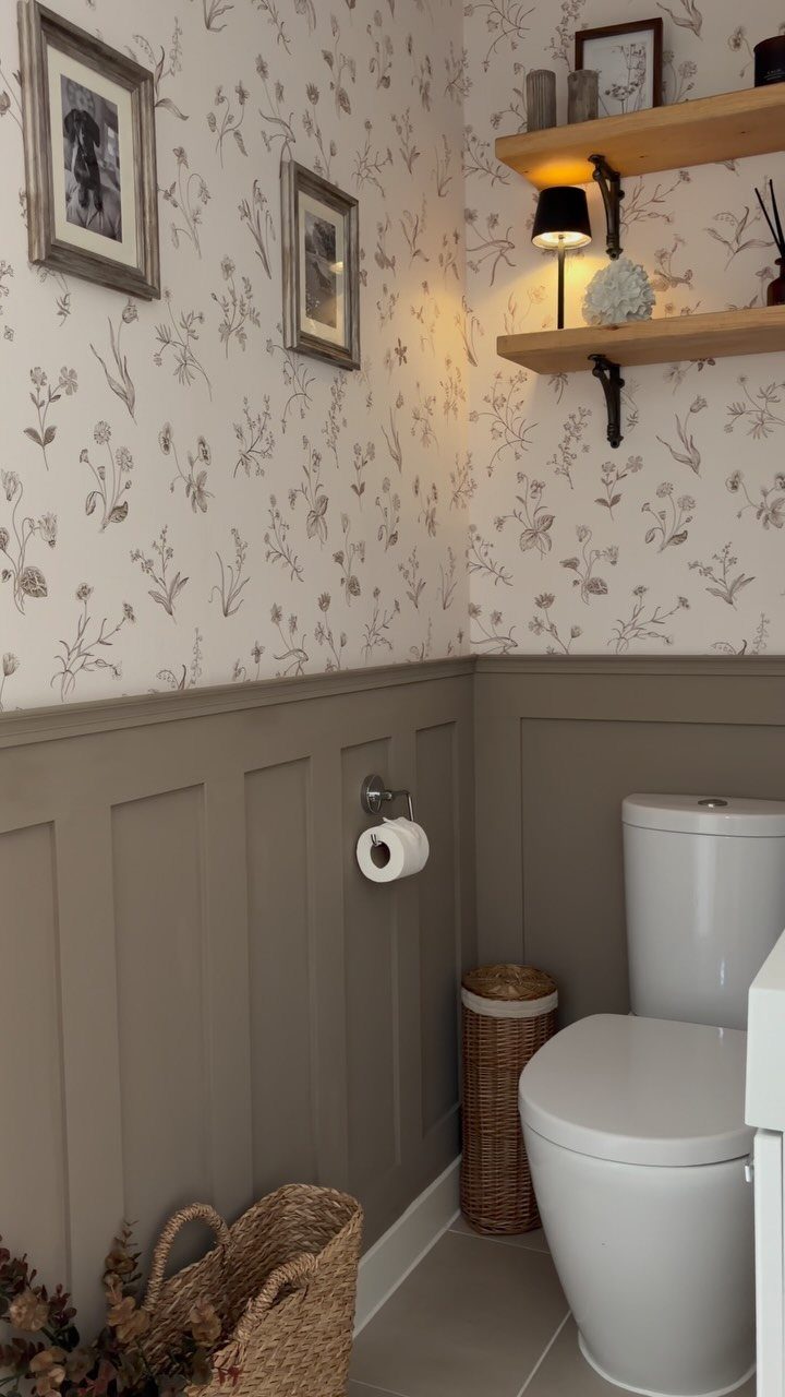 Grey board and batten wainscoting installed in a bathroom with floral wallpaper and a white toilet.