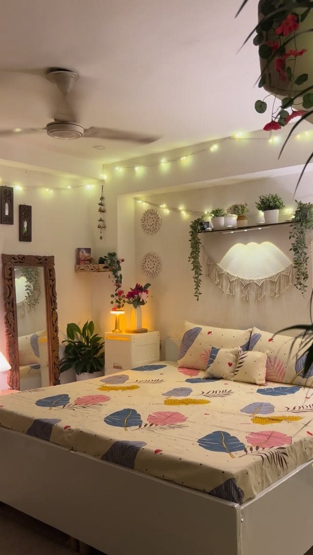 21 Bedroom Wall Decor Ideas With Photos for Every Style 11 Macrame wall hangings and fairy lights decorating a cozy bedroom with plants and a bed.