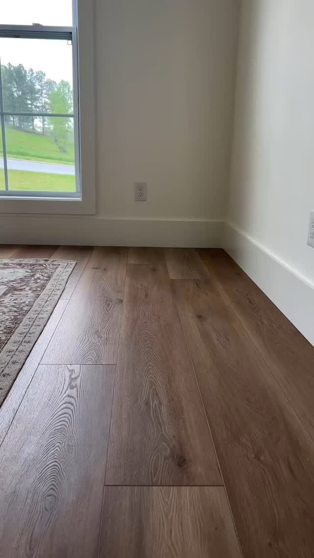 White baseboard molding runs along the bottom of light walls above wood flooring.