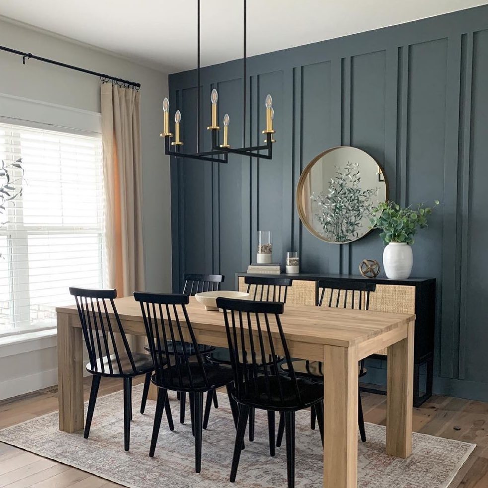 Dining room with a dark teal board and batten accent wall and wooden table.