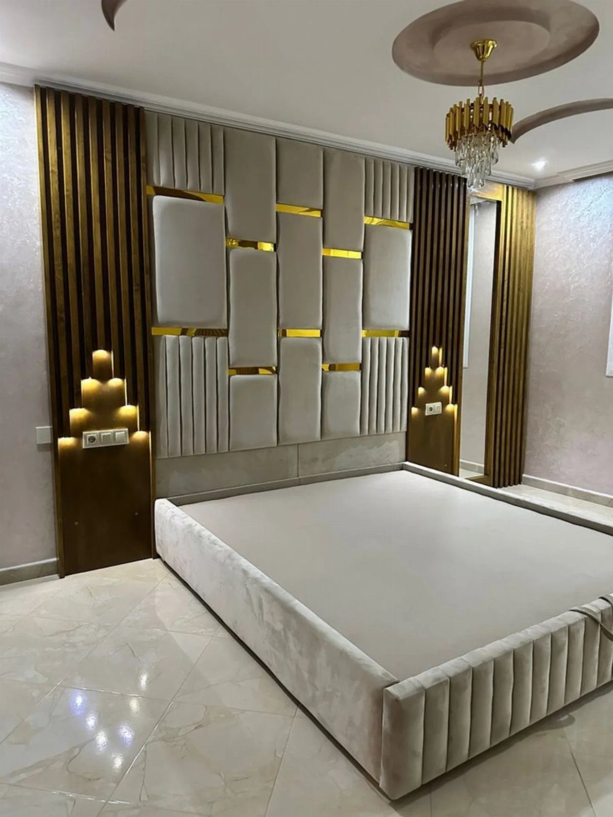 20 Bedroom Wall Designs for Accent, Texture and Art 10 Large upholstered headboard with gold accents and vertical tufting behind a modern bed.