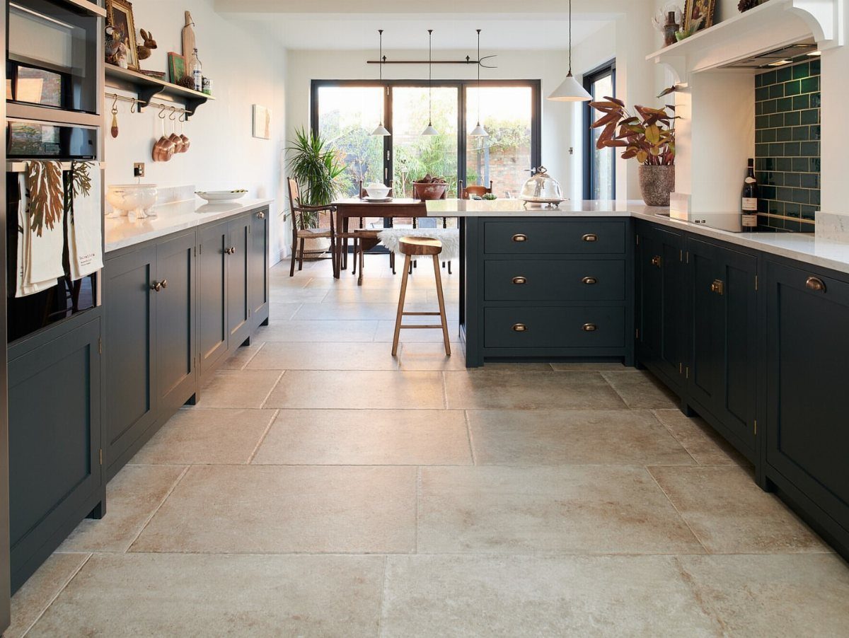 Kitchen Floor Tiles Design: 13 Ideas for Stone, Ceramic & Patterned Floors 3 Large beige rectangular floor tiles in a modern kitchen with dark blue cabinets.