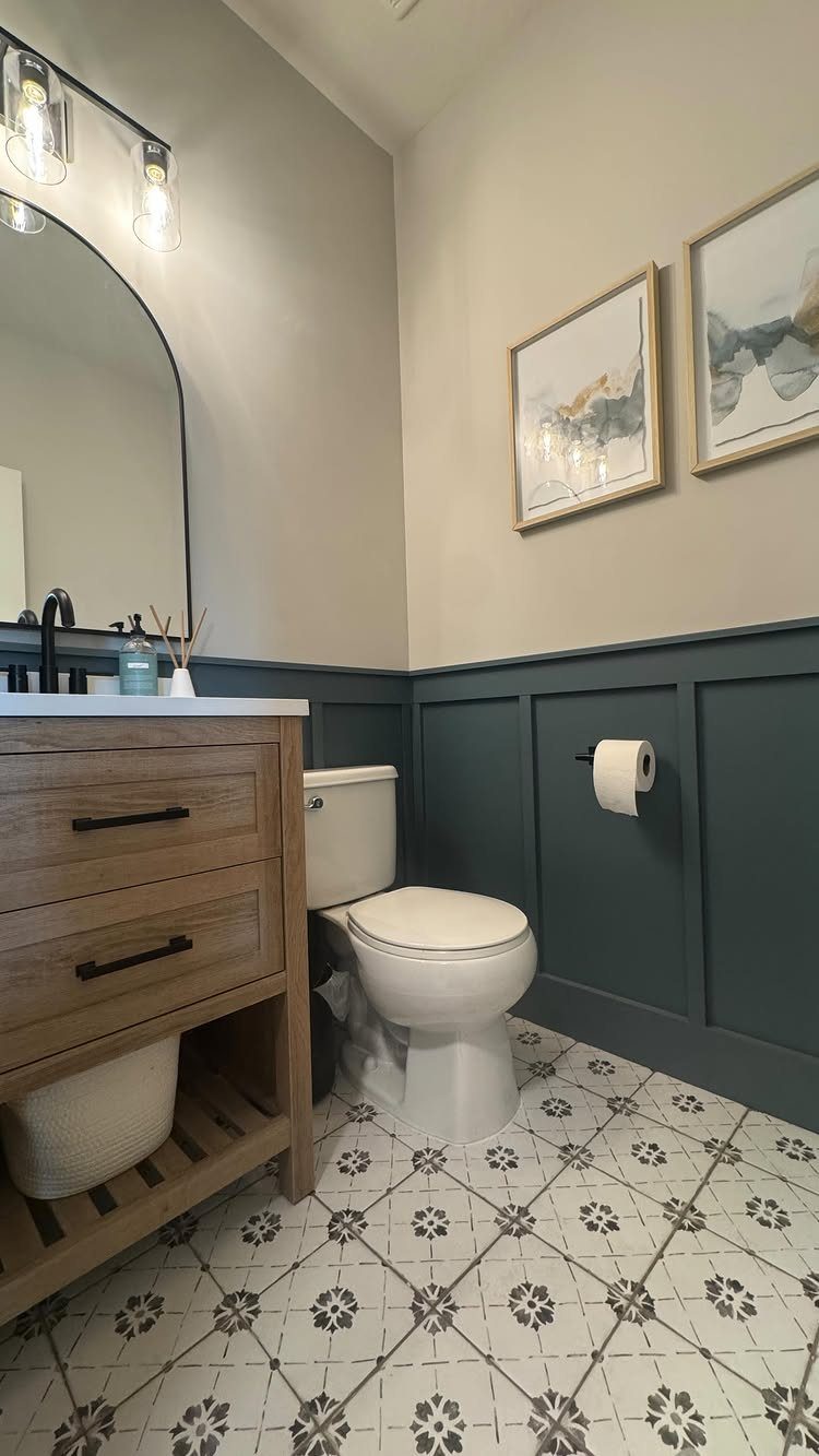 Dark teal wainscotting installed on the lower walls of a modern bathroom with patterned tile floors.