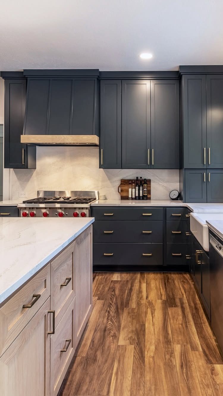 15 Kitchen Renovation Ideas for Getting the Function Back Into the Room 11 Dark blue kitchen cabinets with gold hardware and white marble countertops over wood floors.