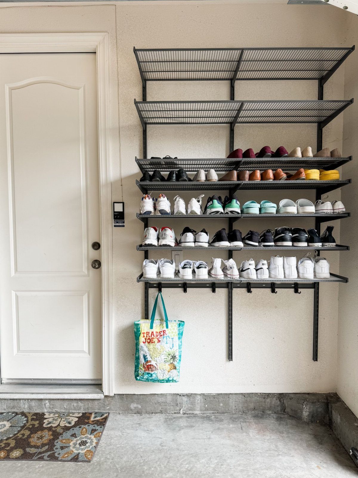 Black metal wire racks mounted on a white wall holding multiple rows of various shoes.