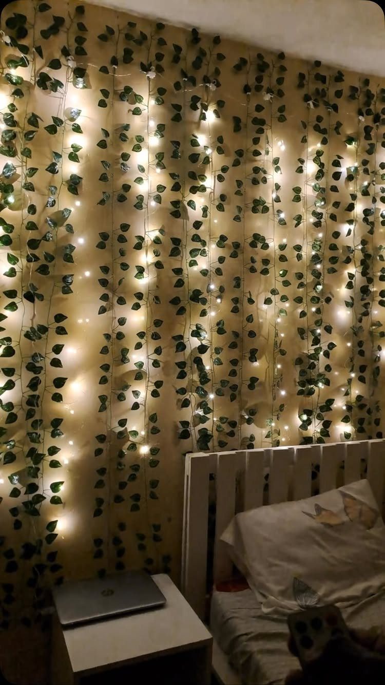 21 Bedroom Wall Decor Ideas With Photos for Every Style 19 Green ivy vines hanging vertically on a wall intertwined with glowing warm white fairy lights.