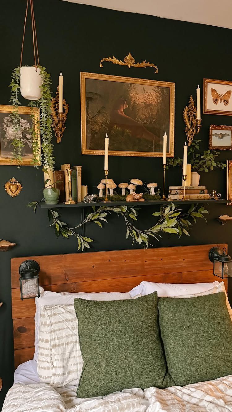 20 Bedroom Wall Designs for Accent, Texture and Art 1 Framed paintings and gold decor arranged on a dark green wall above a wooden bed headboard.