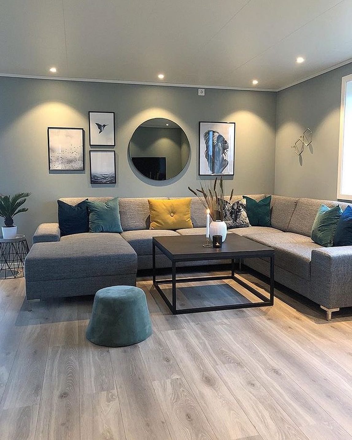 Light grey wood floors in a modern living room with a grey sofa and black coffee table.