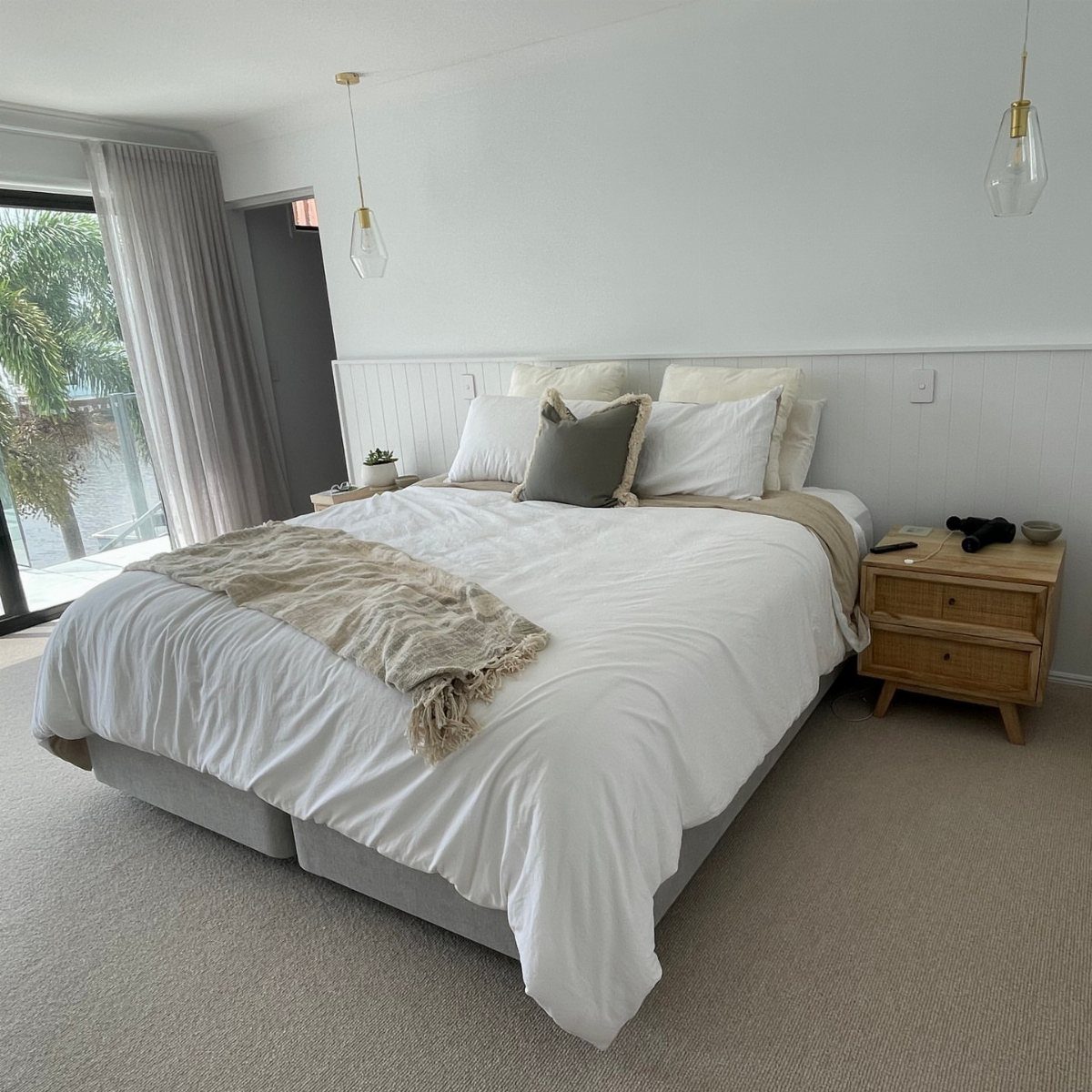 20 Bedroom Wall Designs for Accent, Texture and Art 16 White bed with neutral linens sits against a wall with white vertical wainscoting half-wall design.