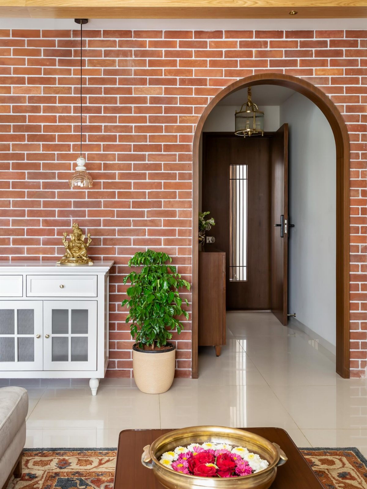 Red brick accent wall with an arched doorway and a white sideboard in a bright room.