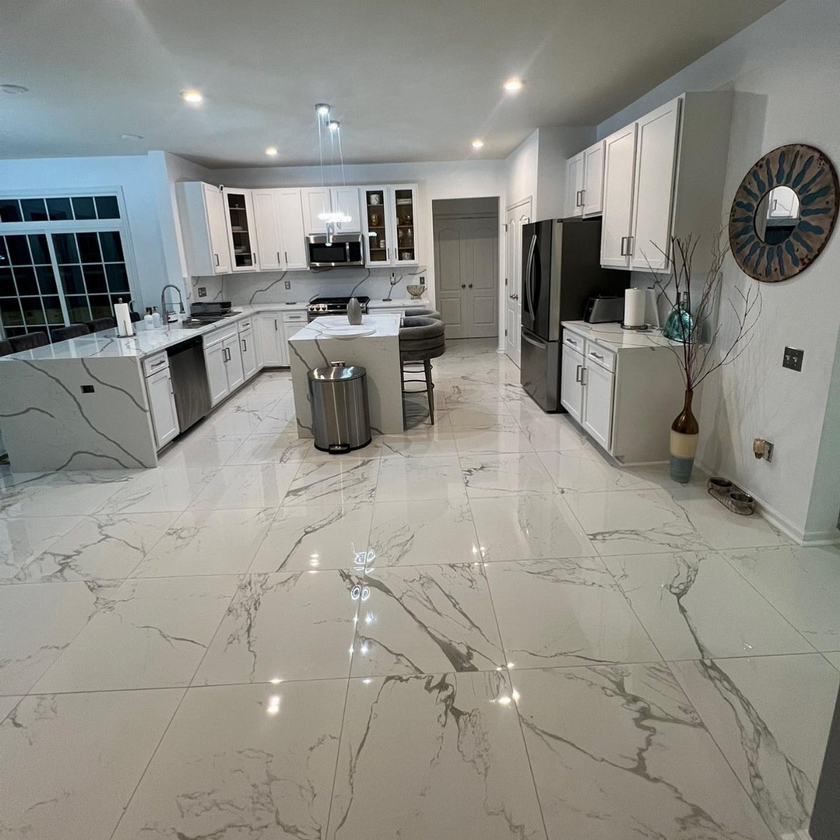 Large white marble-patterned tiles covering the floor of a modern, bright kitchen.
