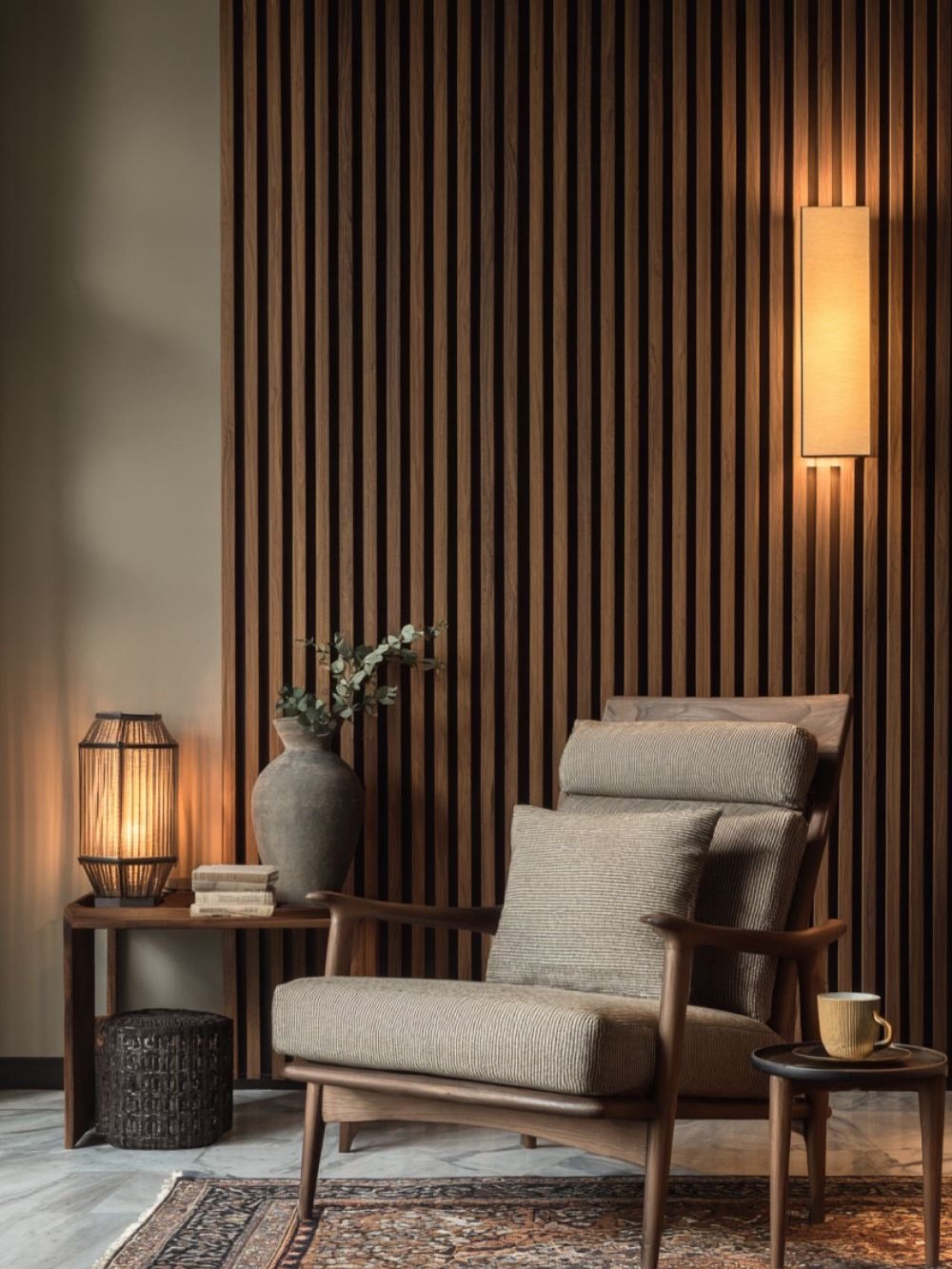 Vertical dark wood slats form a modern paneled wall behind a stylish armchair and side table.