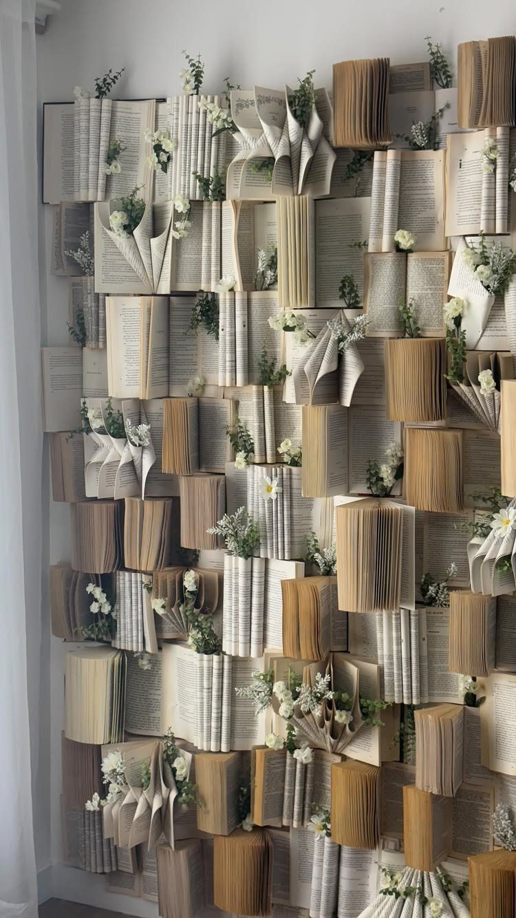 21 Bedroom Wall Decor Ideas With Photos for Every Style 15 Open books with fanned pages and small white flowers mounted on a white wall.