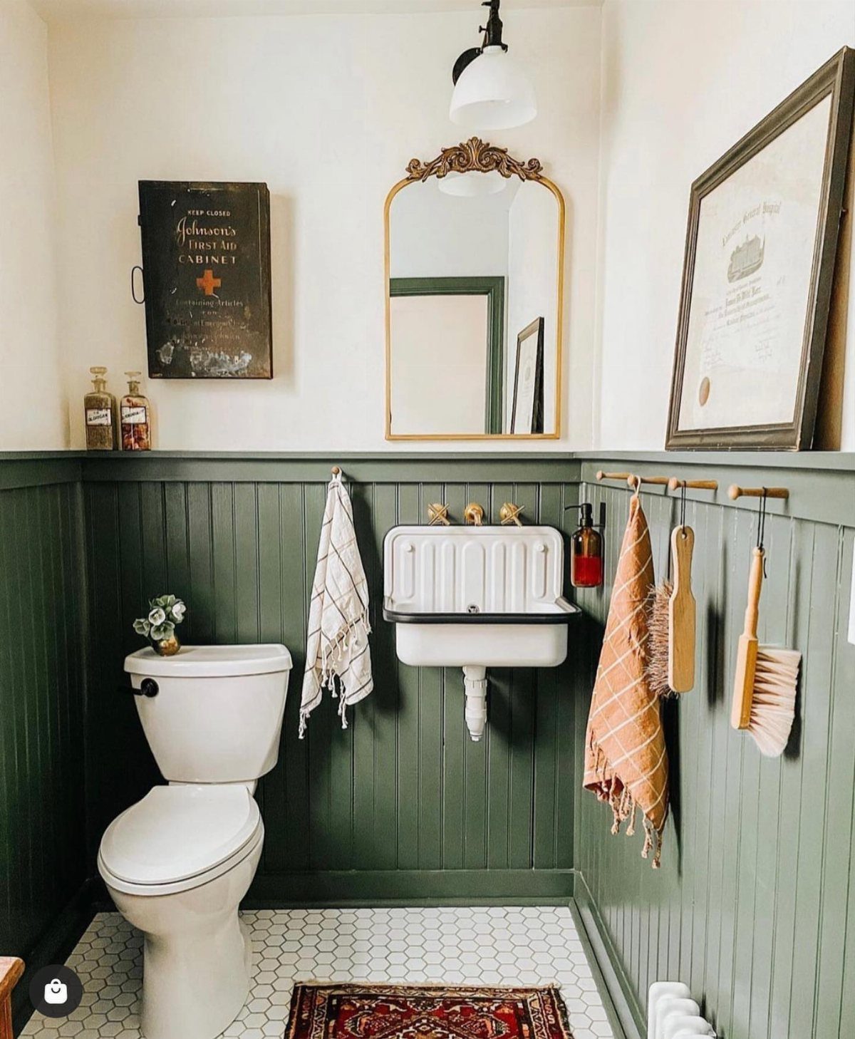 Dark green beadboard wainscoting installed in a small bathroom with a white toilet and sink.