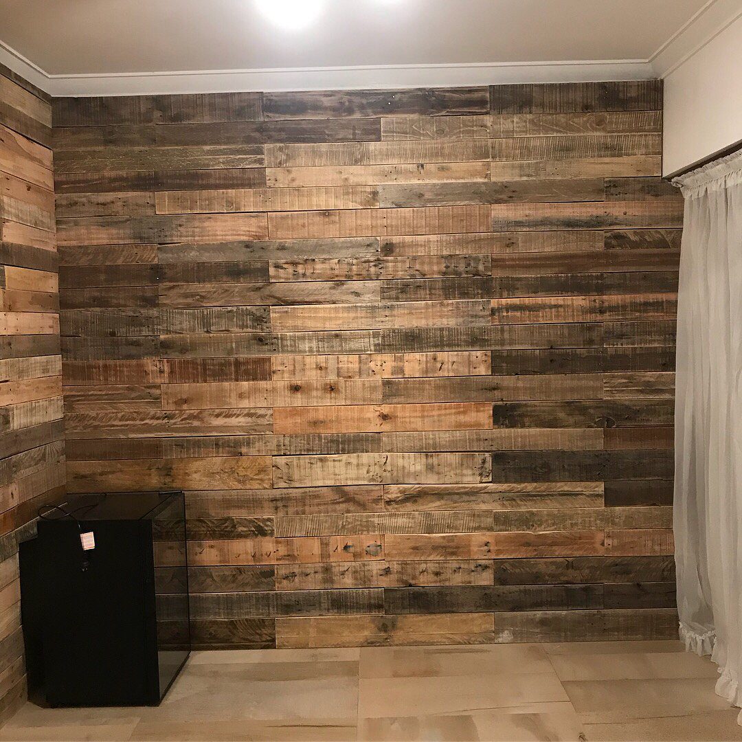 Weathered horizontal wooden planks covering a wall in a rustic interior setting.