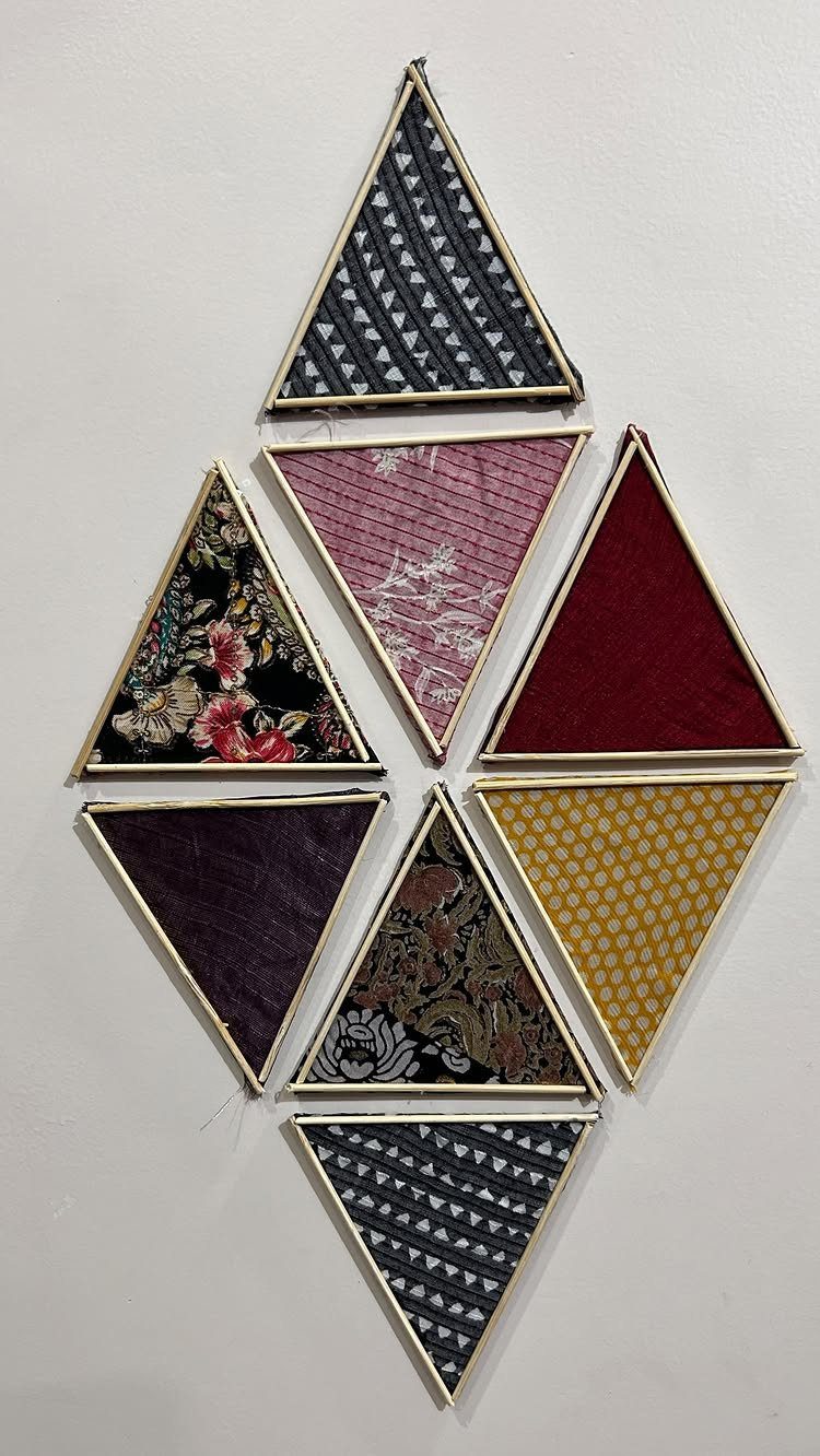 21 Bedroom Wall Decor Ideas With Photos for Every Style 8 Triangular frames containing various patterned scrap cloths arranged in a diamond shape on a wall.