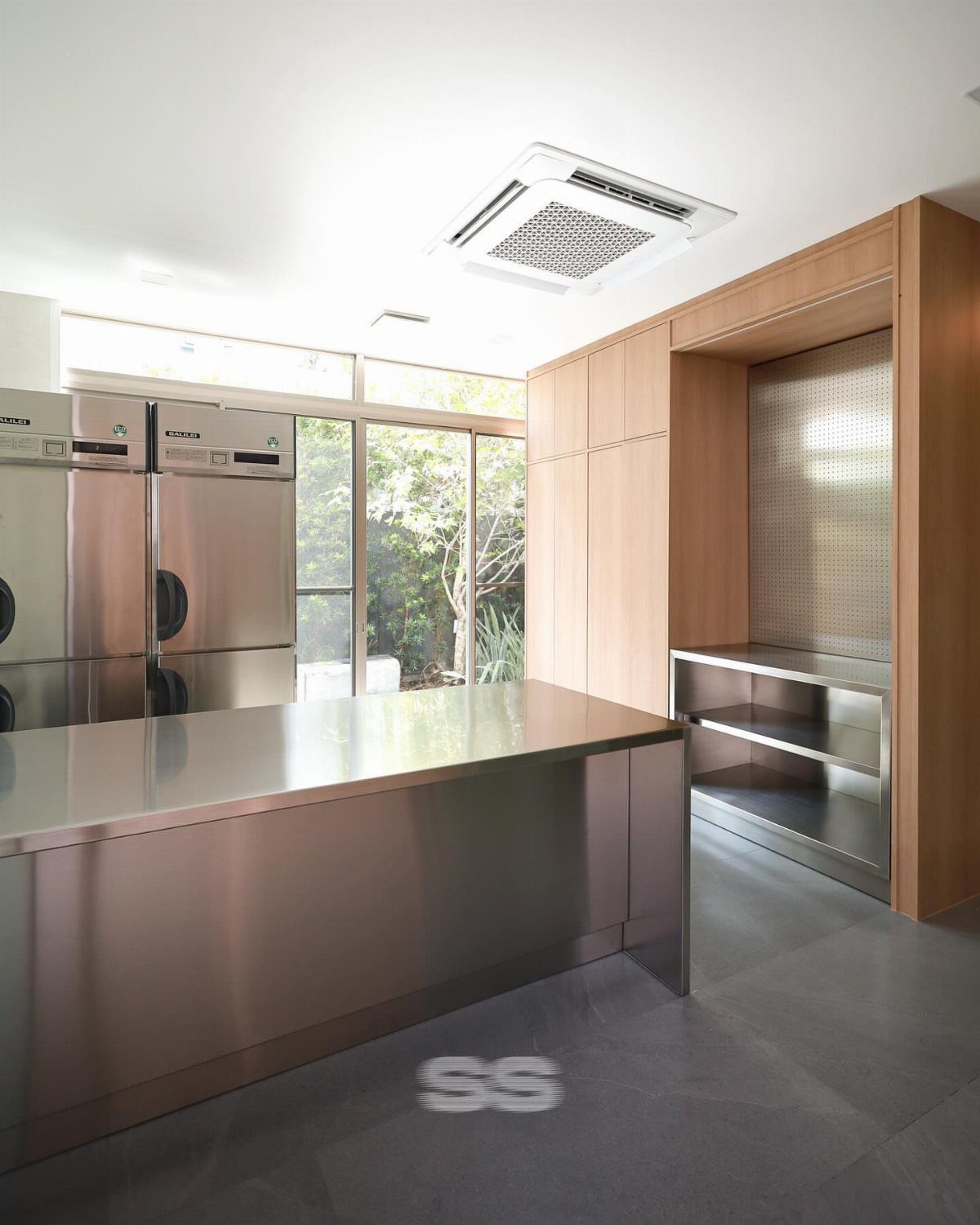 15 Kitchen Renovation Ideas for Getting the Function Back Into the Room 14 Stainless steel kitchen island and wooden cabinetry with built-in metal shelving in a bright room.
