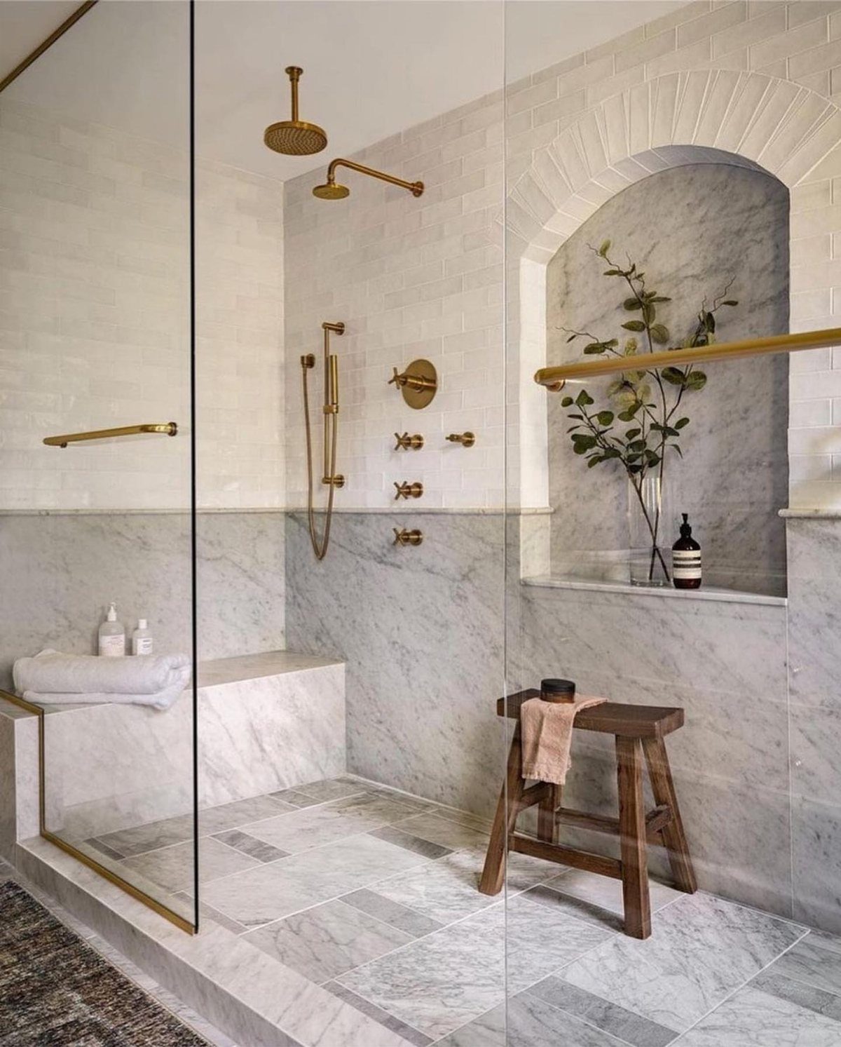 Marble tile wainscoting and white subway tiles in a modern bathroom with gold fixtures.