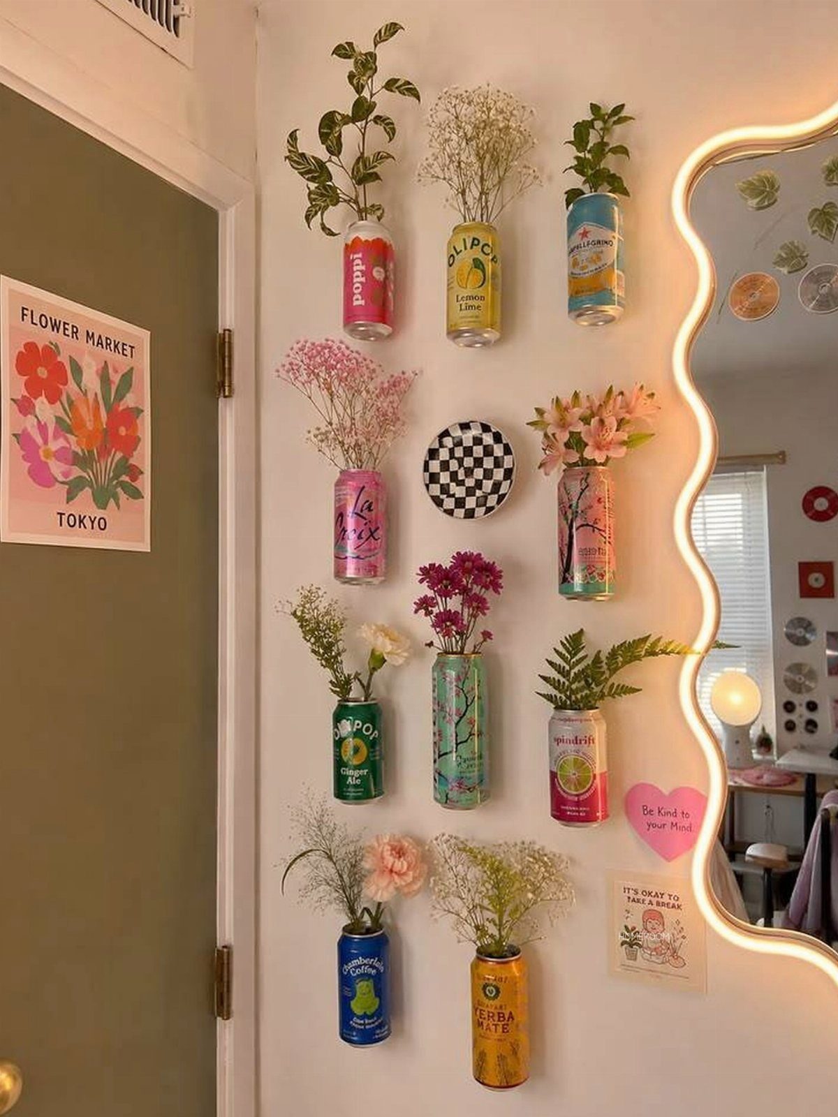 21 Bedroom Wall Decor Ideas With Photos for Every Style 17 Colorful beverage cans used as wall vases with various flowers on a white wall.