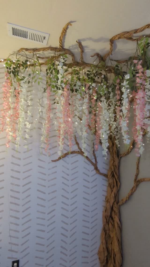 21 Bedroom Wall Decor Ideas With Photos for Every Style 9 Decorative tree branch wall art with hanging pink flowers and twinkling fairy lights.