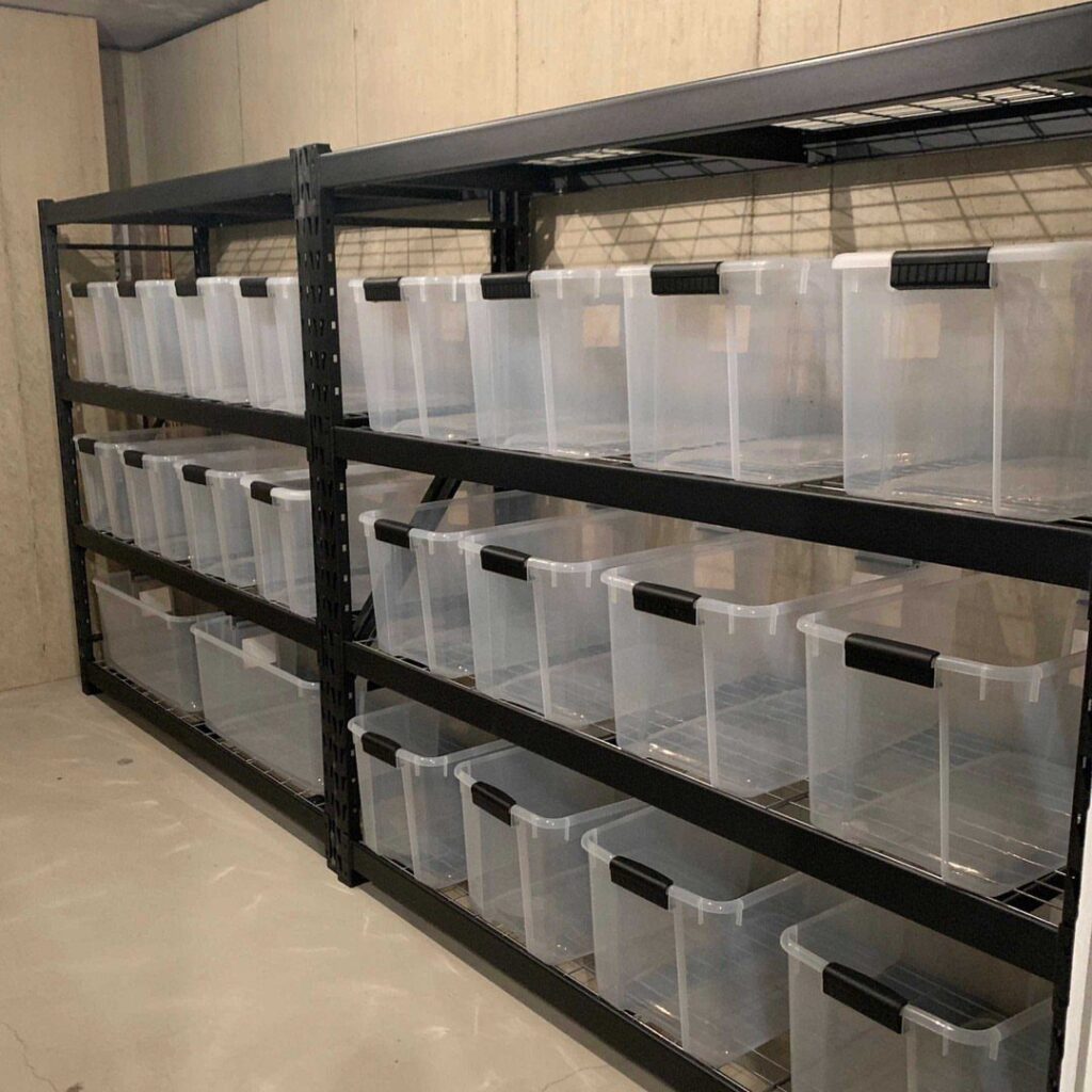 Clear plastic storage containers organized on black metal shelving units in a basement.