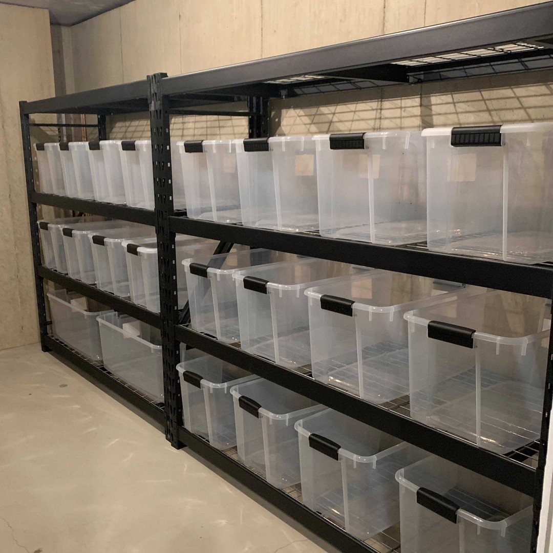 Clear plastic storage containers organized on black metal shelving units in a basement.