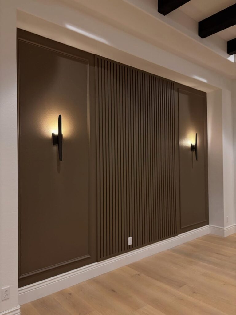 Brown accent wall with traditional molding panels and a central section of vertical wood slats.