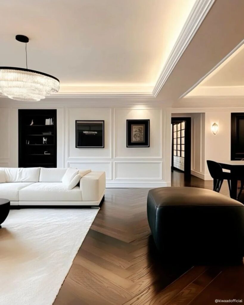 Modern living room with white furniture and dark wood chevron patterned flooring.