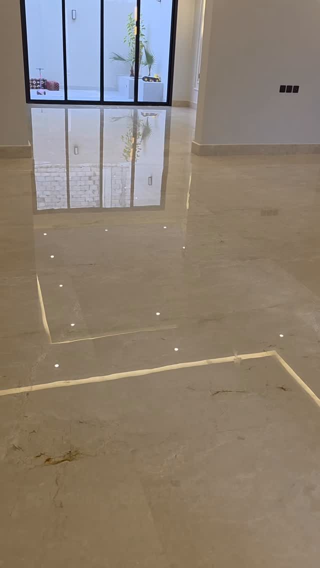 Polished beige marble flooring with reflective surfaces and decorative inlaid lines in a modern room.