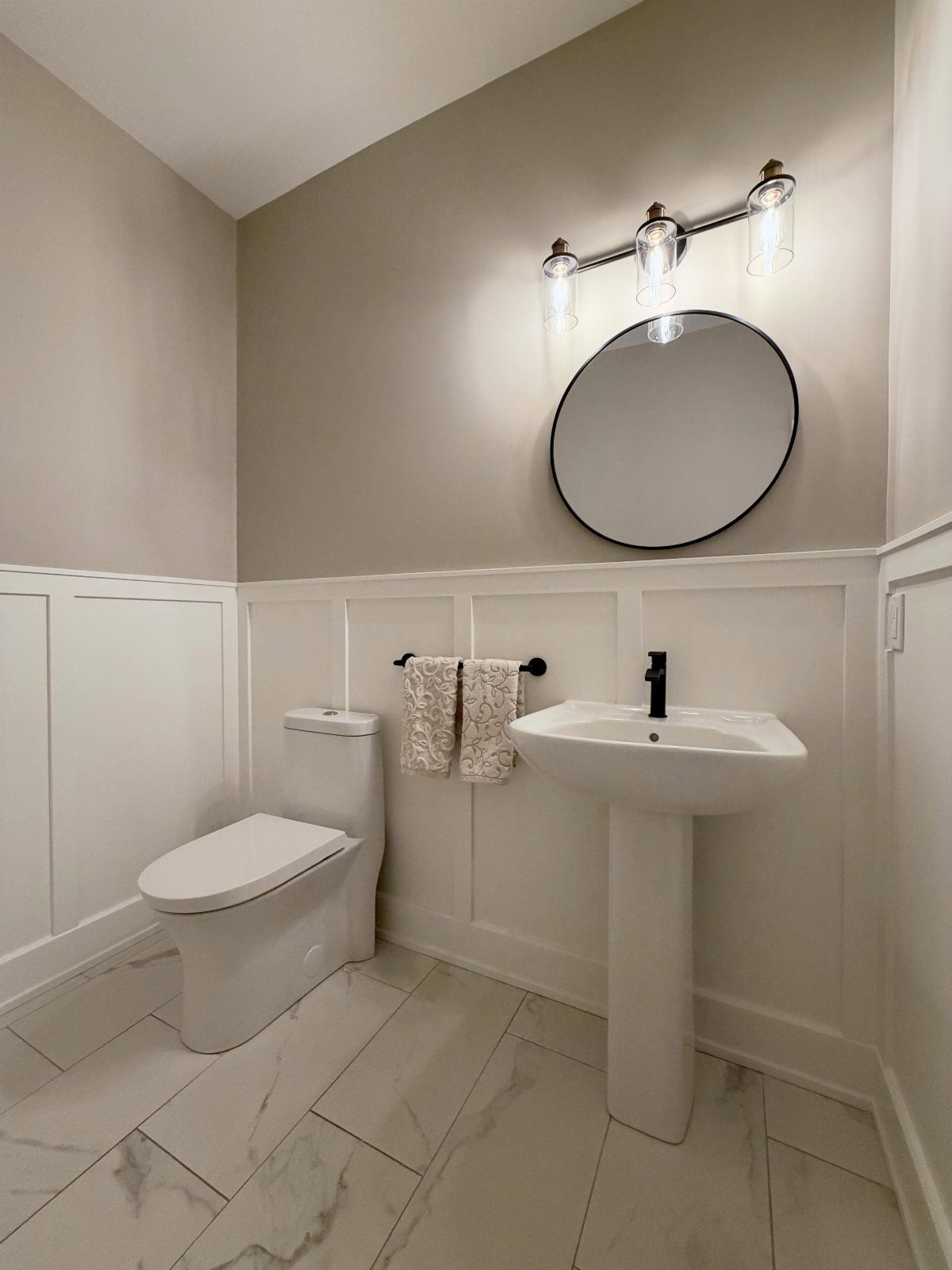 White wainscotting panels installed on the lower walls of a modern bathroom with a pedestal sink.