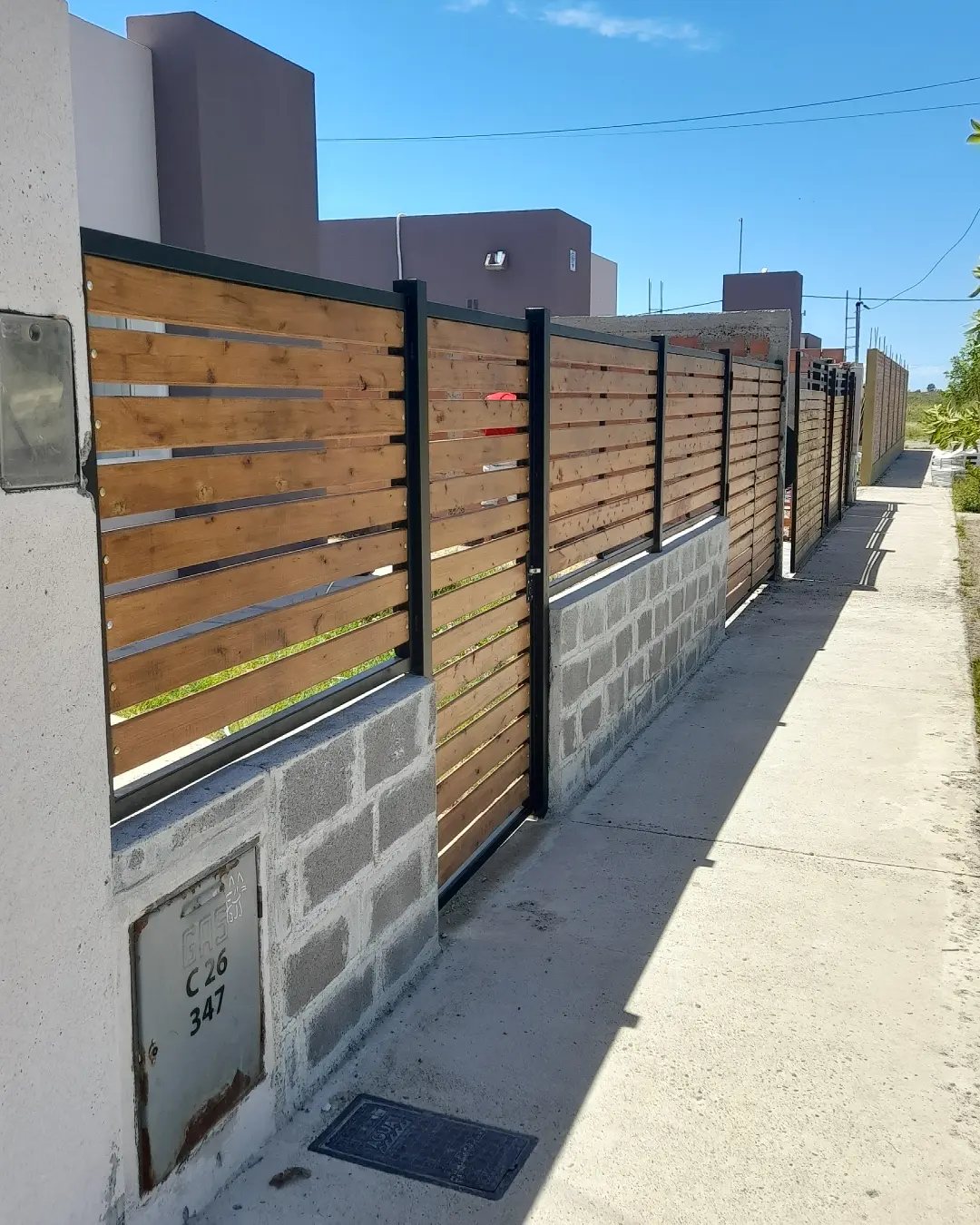 5 Wood Fence Horizontal Ideas for Every Yard 2 Horizontal wooden slats in black metal frames mounted on a concrete block wall.