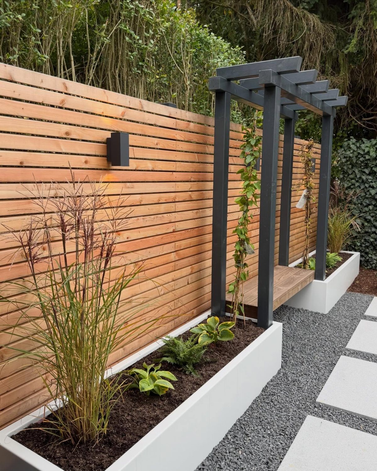 5 Wood Fence Horizontal Ideas for Every Yard 5 Horizontal cedar wood slat fence bordering a modern garden with white planters and a dark pergola.