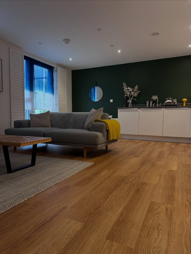 Honey oak wood plank flooring in a modern living room with a grey sofa.