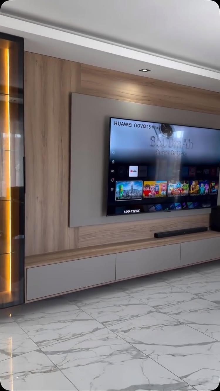 Modern TV wall unit with wood paneling, a large television, and a floating grey media console.
