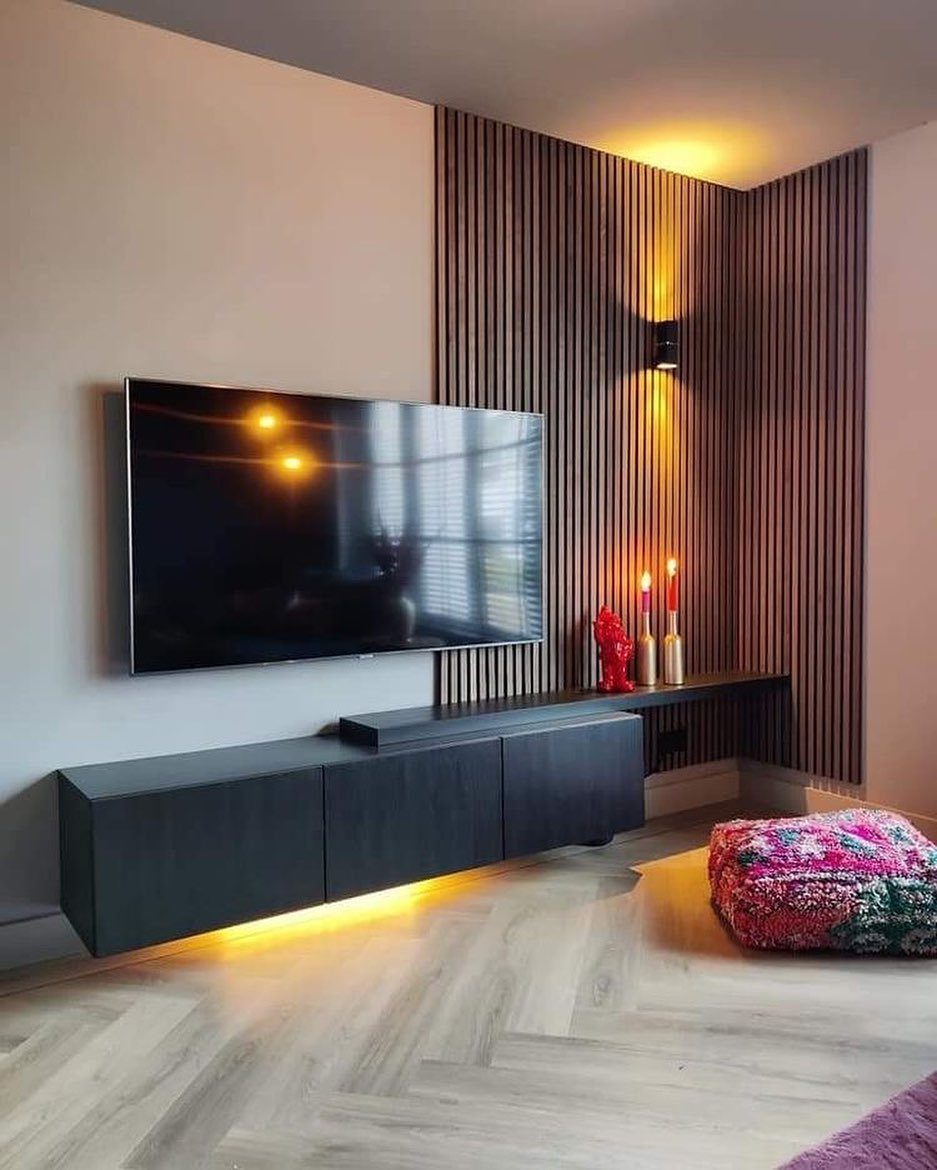 Vertical wooden slats decorate a corner wall next to a mounted television and dark floating console.