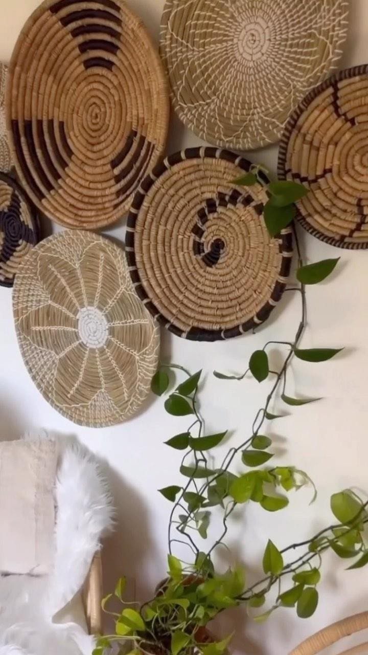 20 Bedroom Wall Designs for Accent, Texture and Art 14 Woven baskets in tan and black patterns arranged on a white wall with a green plant.